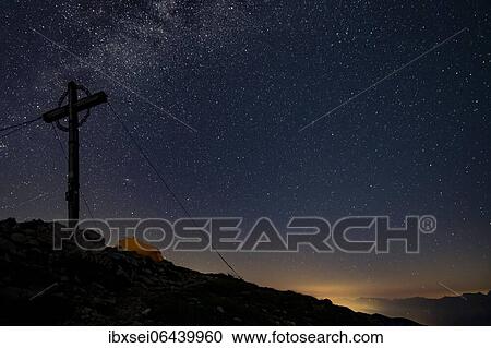 Night sky with stars and milky way over Ammergau mountains, in the foreground summit cross of the Geierkopf with tent, Reutte, Ammergau Alps, Tyrol, Austria, Europe View Large Photo Image Stock Image - Night sky with stars and milky way over Ammergau mountains, in the foreground summit cross of the Geierkopf with tent, Reutte, Ammergau Alps, Tyrol, Austria, Europe. Fotosearch