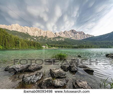 Rocks on the shore, Lake Eibsee lake in front of Zugspitze massif with Zugspitze, dramatic Mammaten clouds, Wetterstein range, near Grainau, Upper Bavaria, Bavaria, Germany, Europe View Large Photo Image Stock Photo - Rocks on the shore, Lake Eibsee lake in front of Zugspitze massif with Zugspitze, dramatic Mammaten clouds, Wetterstein range, near Grainau, Upper Bavaria, Bavaria, Germany, Europe. Fotosearch