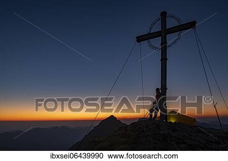 Sunrise over Ammergau mountains, in the foreground summit cross of the Geierkopf with mountaineer and tent, Reutte, Ammergau Alps, Tyrol, Austria, Europe View Large Photo Image Stock Image - Sunrise over Ammergau mountains, in the foreground summit cross of the Geierkopf with mountaineer and tent, Reutte, Ammergau Alps, Tyrol, Austria, Europe. Fotosearch