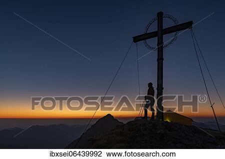 Sunrise over Ammergau mountains, in the foreground summit cross of the Geierkopf with mountaineer and tent, Reutte, Ammergau Alps, Tyrol, Austria, Europe View Large Photo Image Stock Image - Sunrise over Ammergau mountains, in the foreground summit cross of the Geierkopf with mountaineer and tent, Reutte, Ammergau Alps, Tyrol, Austria, Europe. Fotosearch