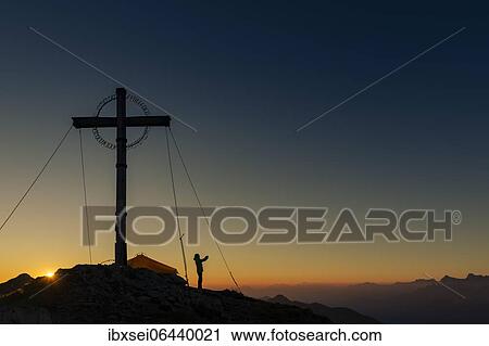 Sunrise over Ammergau mountains, in the foreground summit cross of the Geierkopf with mountaineer and tent, Reutte, Ammergau Alps, Tyrol, Austria, Europe View Large Photo Image Stock Image - Sunrise over Ammergau mountains, in the foreground summit cross of the Geierkopf with mountaineer and tent, Reutte, Ammergau Alps, Tyrol, Austria, Europe. Fotosearch