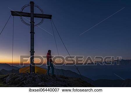 Sunrise over Ammergau mountains, in the foreground summit cross of the Geierkopf with mountaineer and tent, Reutte, Ammergau Alps, Tyrol, Austria, Europe View Large Photo Image Stock Photo - Sunrise over Ammergau mountains, in the foreground summit cross of the Geierkopf with mountaineer and tent, Reutte, Ammergau Alps, Tyrol, Austria, Europe. Fotosearch