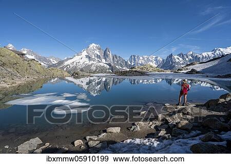 Stock Photo - Young woman in front of mountain panorama, reflection in Lac Blanc, mountain peaks, Grandes Jorasses and Mont Blanc massif, Chamonix-Mont-Blanc, Haute-Savoie, France, Europe. Fotosearch