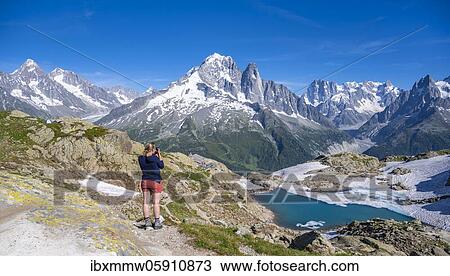Young woman photographs mountain panorama, Lac Blanc, mountain peaks, Grandes Jorasses and Mont Blanc massif, Chamonix-Mont-Blanc, Haute-Savoie, France, Europe View Large Photo Image Stock Image - Young woman photographs mountain panorama, Lac Blanc, mountain peaks, Grandes Jorasses and Mont Blanc massif, Chamonix-Mont-Blanc, Haute-Savoie, France, Europe. Fotosearch