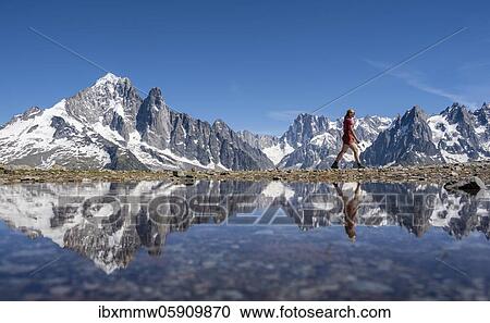 Young woman walking in front of mountain panorama, reflection in Lac Blanc, mountain peaks, Grandes Jorasses and Mont Blanc massif, Chamonix-Mont-Blanc, Haute-Savoie, France, Europe View Large Photo Image Stock Image - Young woman walking in front of mountain panorama, reflection in Lac Blanc, mountain peaks, Grandes Jorasses and Mont Blanc massif, Chamonix-Mont-Blanc, Haute-Savoie, France, Europe. Fotosearch