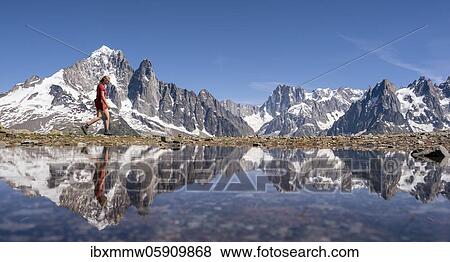 Stock Photo - Young woman walking in front of mountain panorama, reflection in Lac Blanc, mountain peaks, Grandes Jorasses and Mont Blanc massif, Chamonix-Mont-Blanc, Haute-Savoie, France, Europe. Fotosearch
