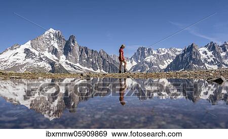 Stock Photo - Young woman walking in front of mountain panorama, reflection in Lac Blanc, mountain peaks, Grandes Jorasses and Mont Blanc massif, Chamonix-Mont-Blanc, Haute-Savoie, France, Europe. Fotosearch