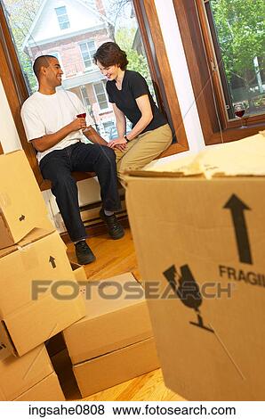 Couple drinking red wine in packed up apartment View Large Photo Image Stock Photo - Couple drinking red wine in packed up apartment. Fotosearch
