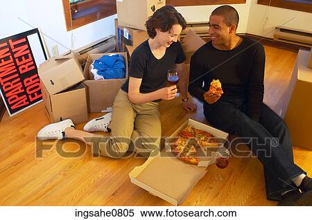 Stock Photography - Couple having pizza and red wine in empty apartment 1. Fotosearch