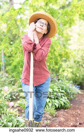 Daydreaming gardener leaning on her shovel View Large Photo Image Stock Image - Daydreaming gardener leaning on her shovel. Fotosearch
