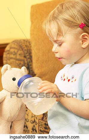 Little girl giving her teddy bear a drink View Large Photo Image Stock Photo - Little girl giving her teddy bear a drink. Fotosearch