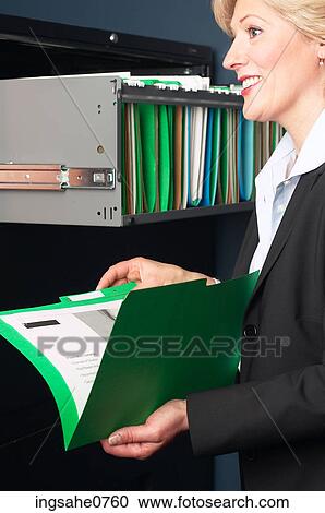 Smiling businesswoman reading file View Large Photo Image Stock Image - Smiling businesswoman reading file. Fotosearch