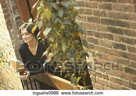 Woman drinking cup of coffee on balcony of brick building View Large Photo Image Stock Photo - Woman drinking cup of coffee on balcony of brick building. Fotosearch