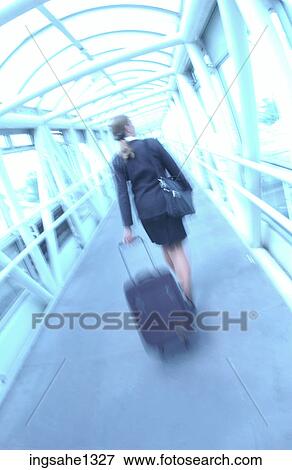 Businesswoman pulling suitcase through glass hallway View Large Photo Image Stock Photo - Businesswoman pulling suitcase through glass hallway . Fotosearch