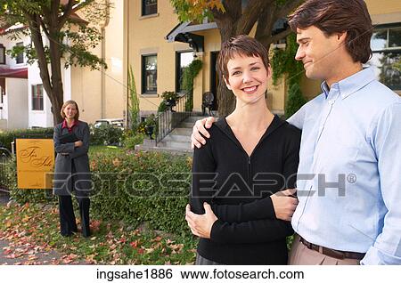 Stock Photograph - Happy couple in front of house BE 5. Fotosearch