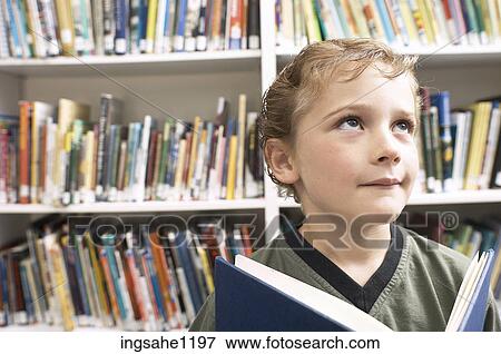 Little boy holding blue book in library 1 View Large Photo Image Stock Photo - Little boy holding blue book in library 1. Fotosearch