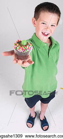 Stock Photo - Little boy holding cupcake . Fotosearch