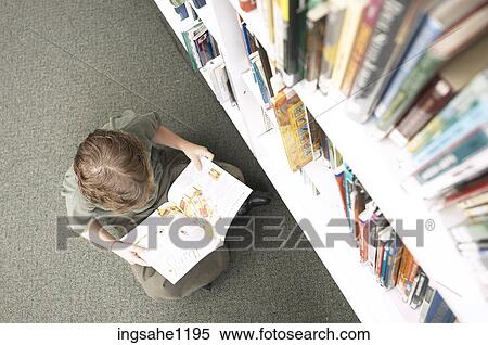 Little boy reading book beside library shelf View Large Photo Image Stock Photography - Little boy reading book beside library shelf. Fotosearch