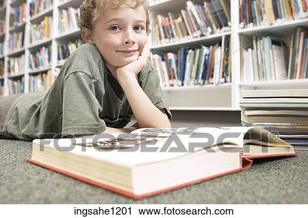 Stock Image - Little boy reading book in library 2. Fotosearch