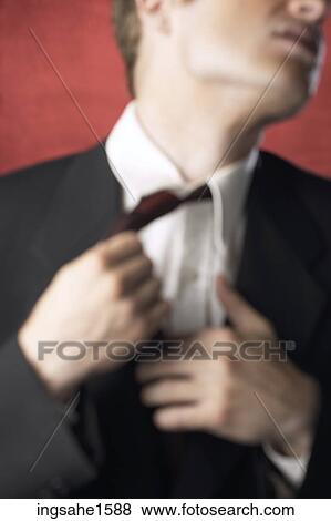 Stock Photo - Man in suit adjusting necktie. Fotosearch