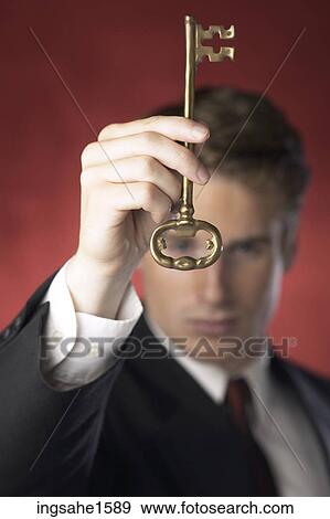 Stock Photo - Man in suit holding antique key. Fotosearch