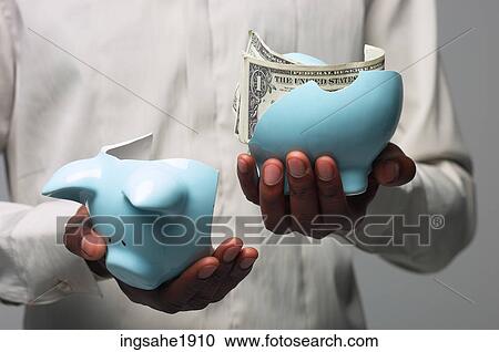 Stock Image - Man in white shirt holding broken piggy bank BE 1. Fotosearch