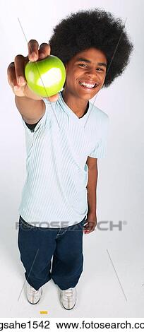 Stock Image - Man with afro holding green apple out. Fotosearch