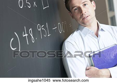 Stock Photography - Math teacher at blackboard holding textbook. Fotosearch