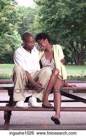 Stock Photograph - Romantic couple sitting on picnic table in park. Fotosearch