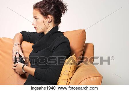 Stock Image - Woman sitting on couch BE 3. Fotosearch