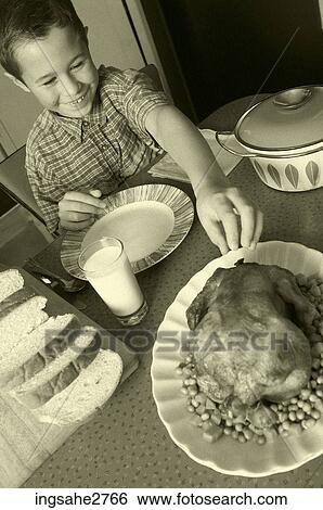 Stock Photograph - 1950s boy at dinner table with chicken . Fotosearch