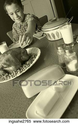 Stock Photography - 1950s boy at dinner table with chicken . Fotosearch