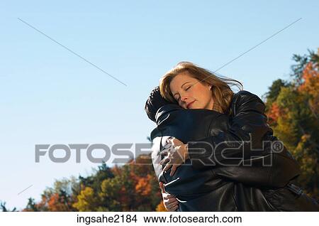 Couple embracing with lake and Fall colours in background View Large Photo Image Picture - Couple embracing with lake and Fall colours in background. Fotosearch