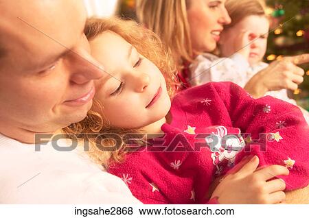 Stock Photo - Family sitting beside Christmas tree . Fotosearch