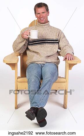 Stock Image - Man in wooden chair enjoying coffee . Fotosearch