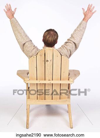 Stock Image - Man in wooden chair with arms raised . Fotosearch