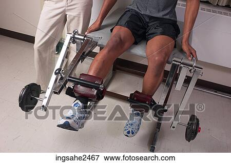 Stock Photo - Patient using physical therapy equipment . Fotosearch