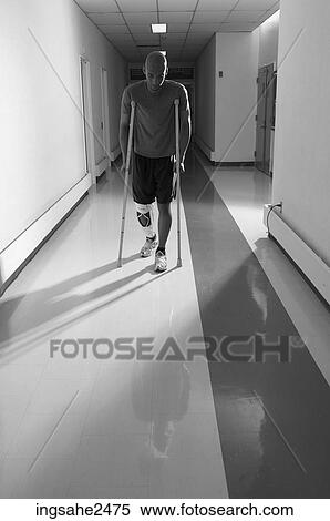 Stock Photography - Patient walking down hallway on crutches. Fotosearch