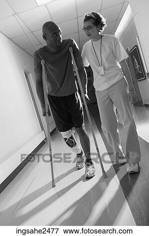 Patient walking down hallway on crutches with nurse an 2 View Large Photo Image Stock Photo - Patient walking down hallway on crutches with nurse an 2. Fotosearch