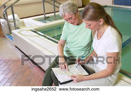 Stock Image - Patient with physiotherapist by pool an 1. Fotosearch