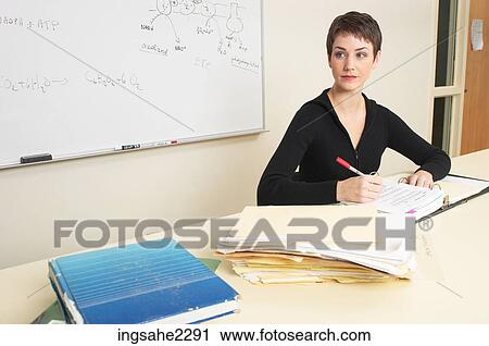 Stock Image - Teacher sitting at desk a82. Fotosearch