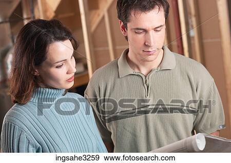 Adult couple looking at blue prints in house under construction View Large Photo Image Stock Photo - Adult couple looking at blue prints in house under construction . Fotosearch