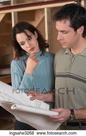 Adult couple looking at blue prints in house under construction View Large Photo Image Stock Photo - Adult couple looking at blue prints in house under construction . Fotosearch
