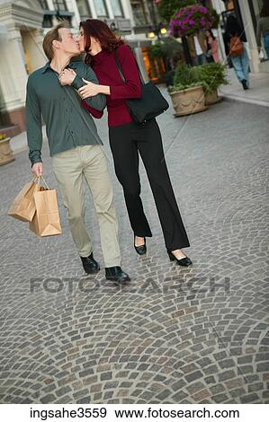Adult couple walking and kissing with shopping bags View Large Photo Image Stock Photo - Adult couple walking and kissing with shopping bags . Fotosearch