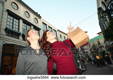 Adult couple with shopping bags pointing View Large Photo Image Picture - Adult couple with shopping bags pointing . Fotosearch