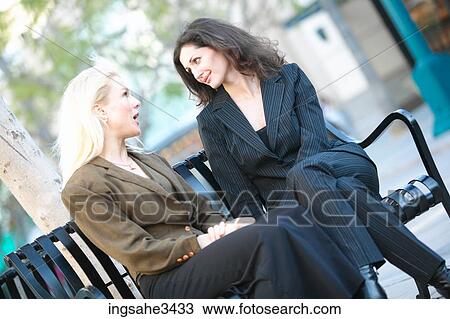 Stock Image - adults sitting on bench and talking . Fotosearch