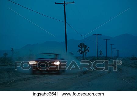 Stock Image - Car driving on dirt road at night . Fotosearch