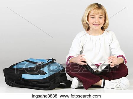 Caucasian blonde girl sitting cross legged with a backpack and a book View Large Photo Image Stock Photo - Caucasian blonde girl sitting cross legged with a backpack and a book. Fotosearch