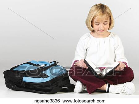 Caucasian blonde girl sitting cross legged with a backpack and reading View Large Photo Image Stock Photograph - Caucasian blonde girl sitting cross legged with a backpack and reading . Fotosearch