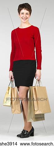Picture - Cheerful young woman carrying shopping bags. Fotosearch
